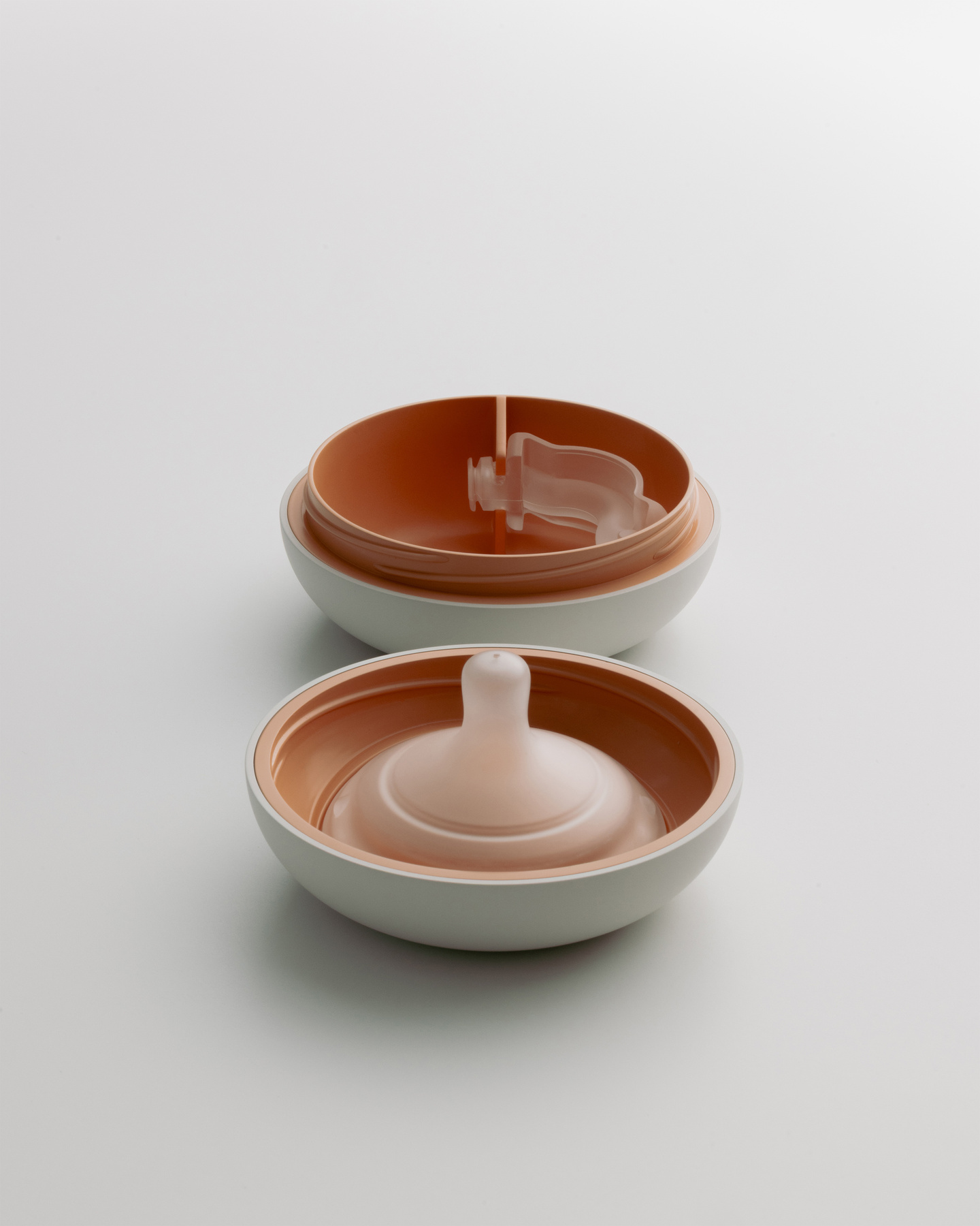 Two molded plastic housing components of the breast pump stacked together.