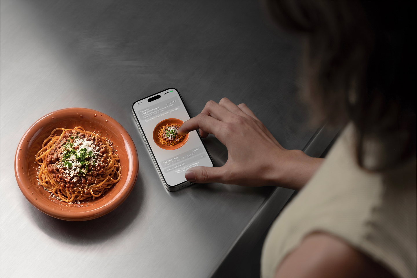 Hand holding a smart insulin pen app near a plate of food during daily use