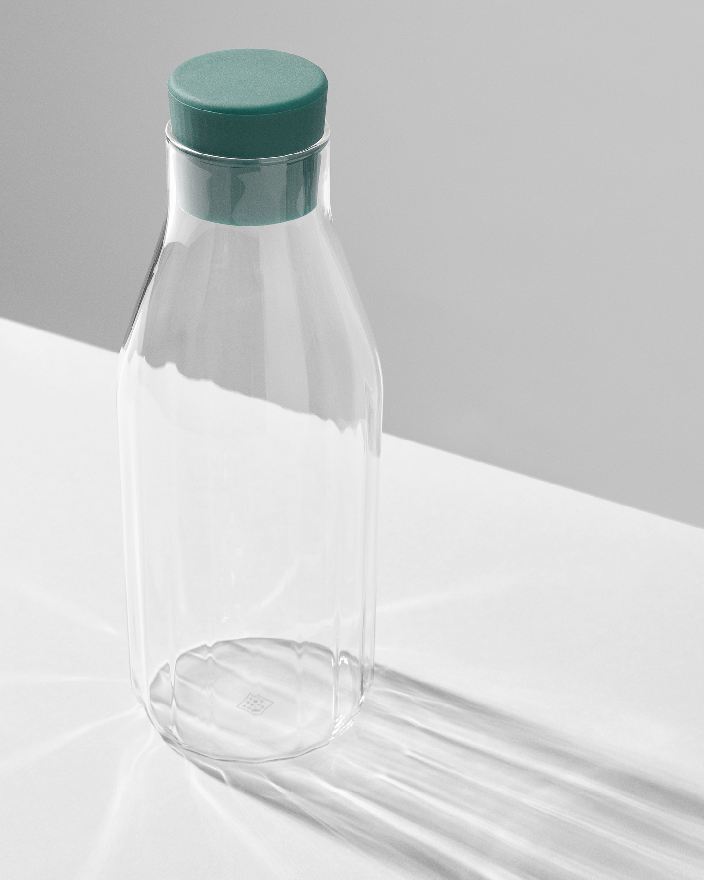 Inset showing a clear glass carafe with a green cap on a white surface