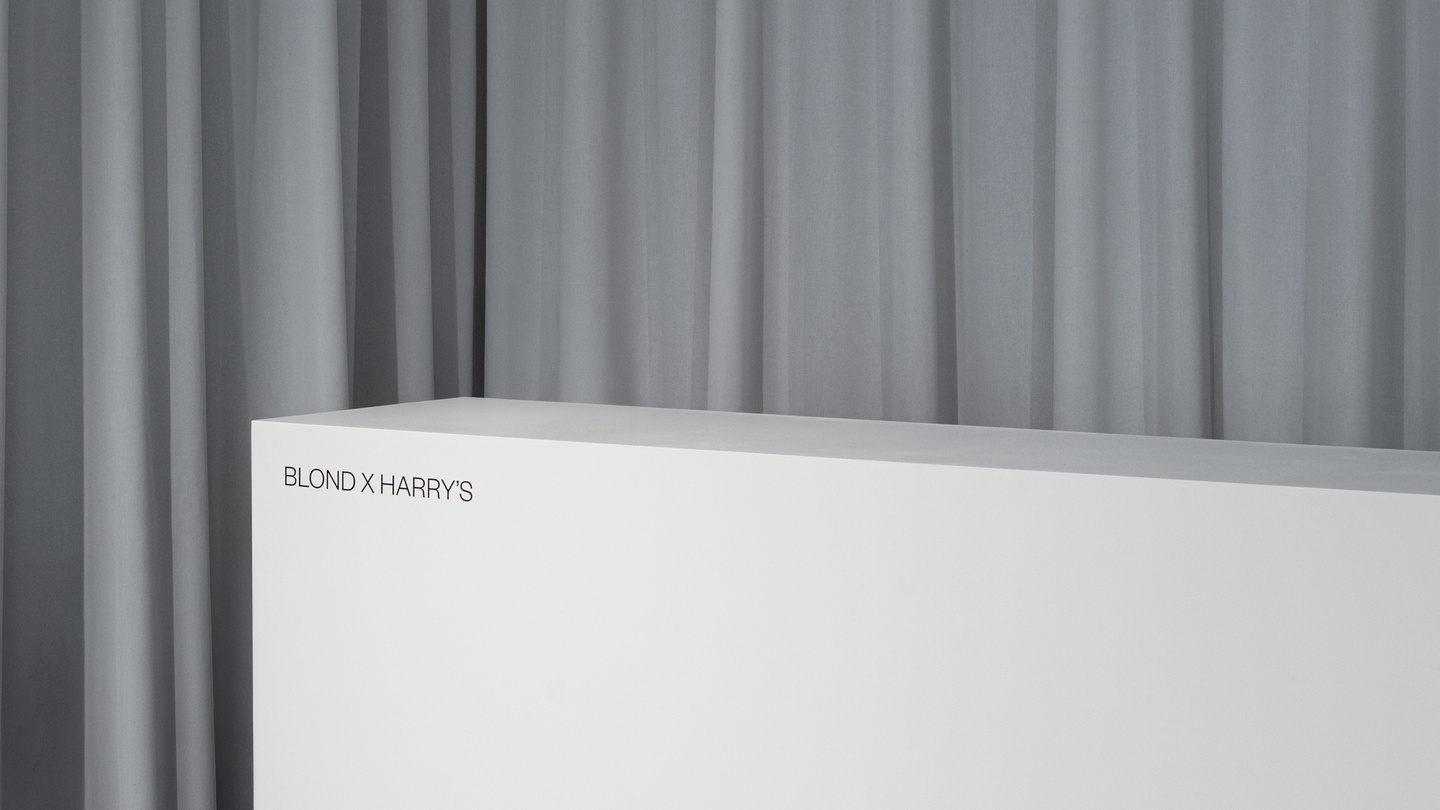 Wide photo of exhibition space featuring white display counter against grey curtain backdrop