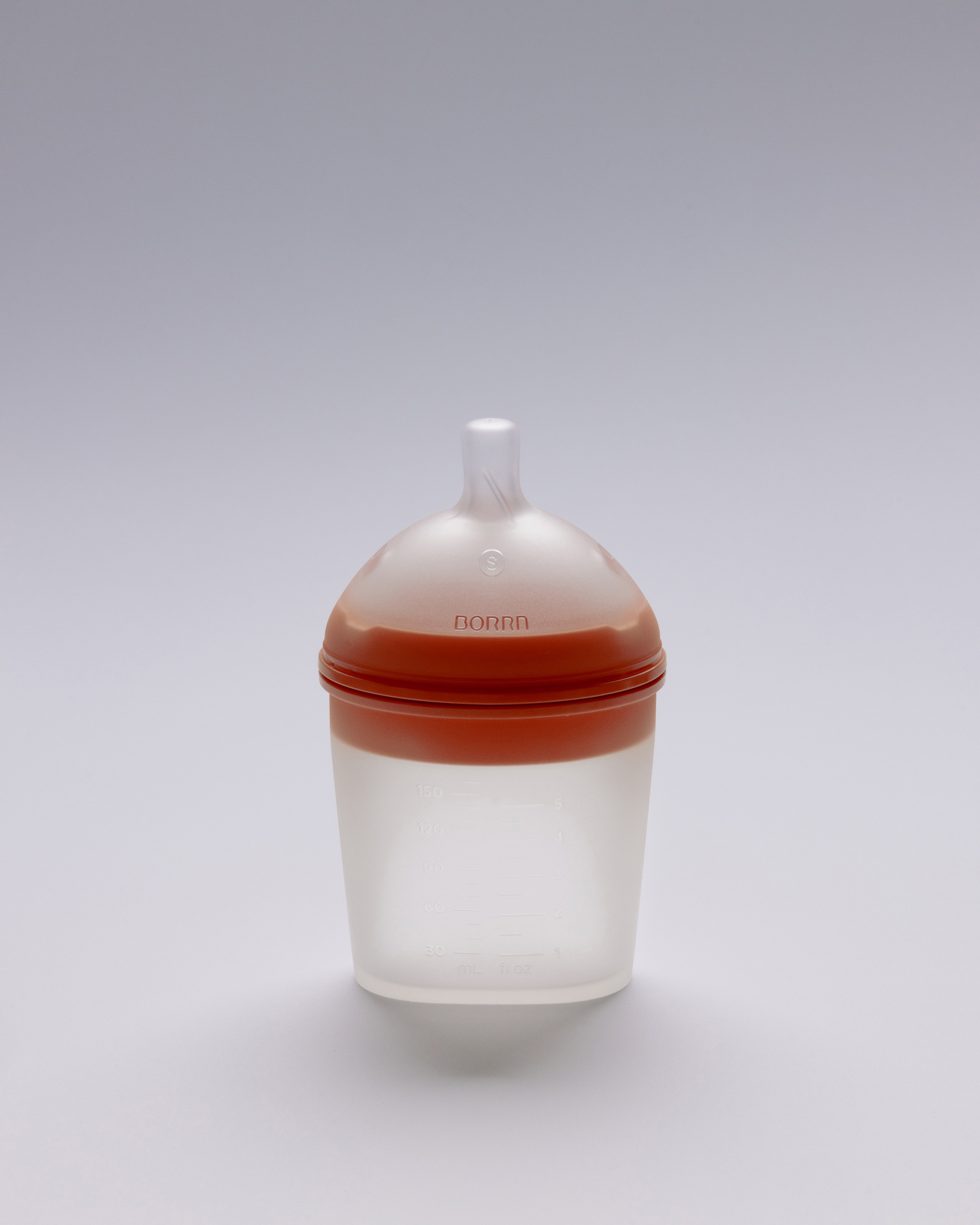 Distant view of small white and orange silicone feeding bottle.