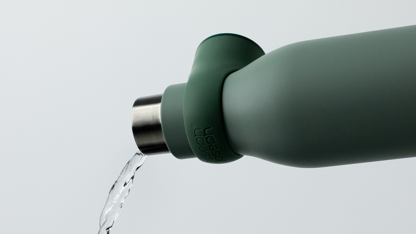 Water stream pouring from a green reusable water bottle