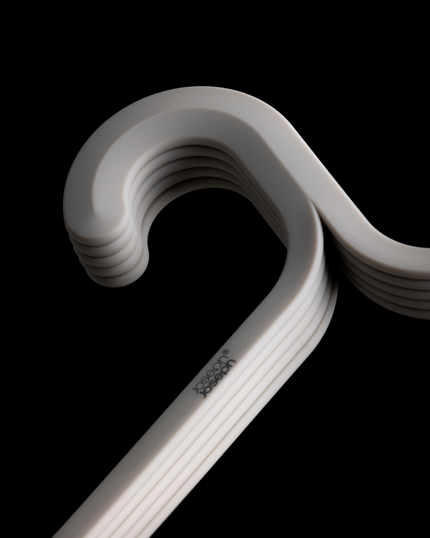 Close-up view of stacked grey coat hanger necks against a black background