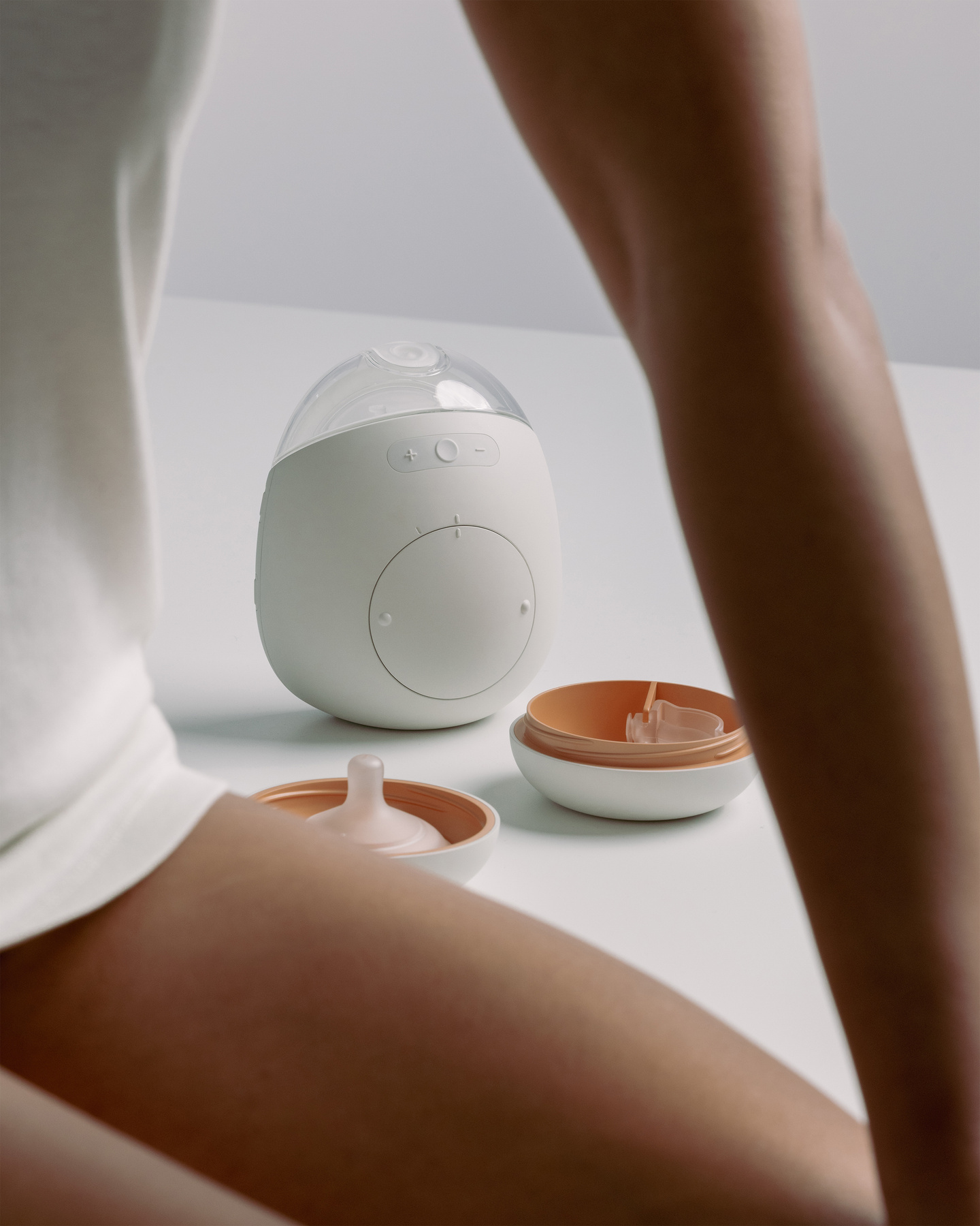 Seated woman with the white Avira breast pump displayed in the background.