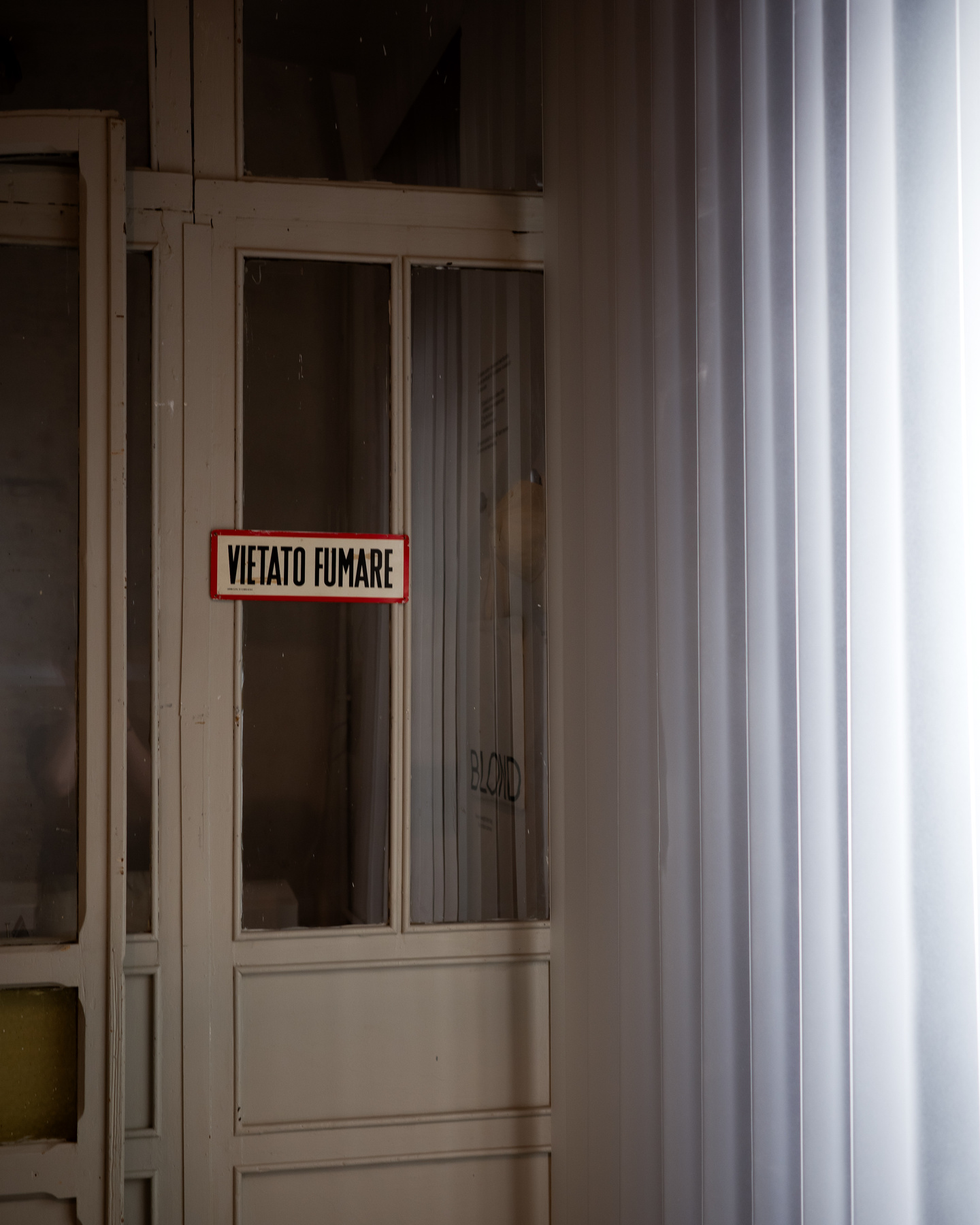 Looking through sheer white curtain into exhibition room space