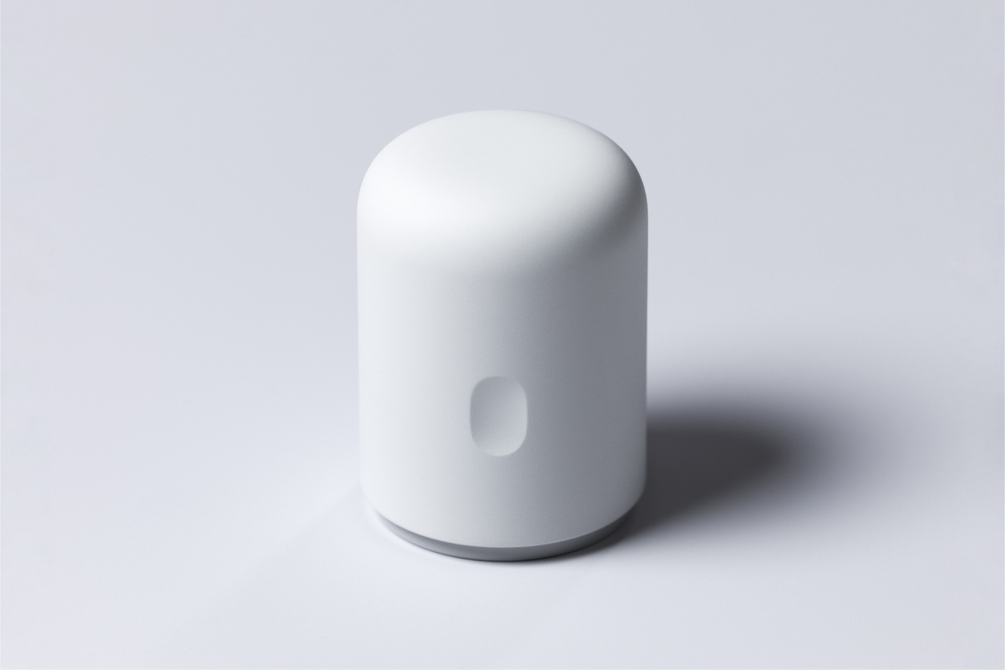 Matte white cylindrical continuous glucose monitor applicator standing upright on a neutral background