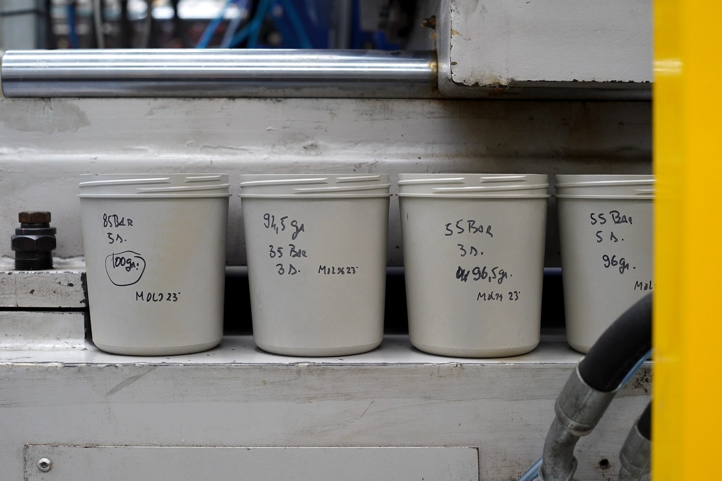 Beige reusable tub containers inside an industrial washing machine chamber.