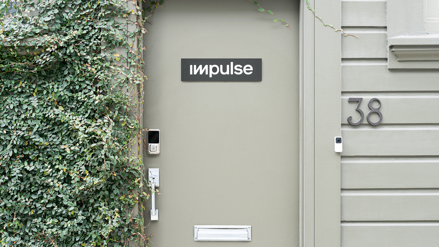 Grey entrance door of a studio building with green climbing plant