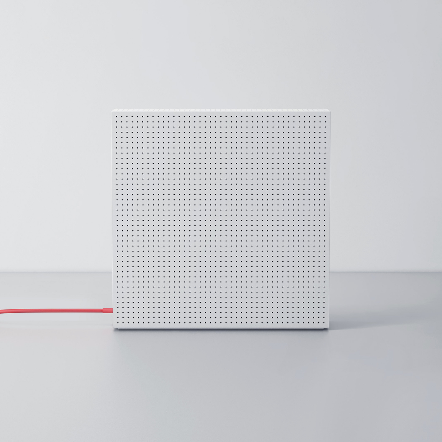 Square white perforated enclosure standing with a red cable on a grey surface