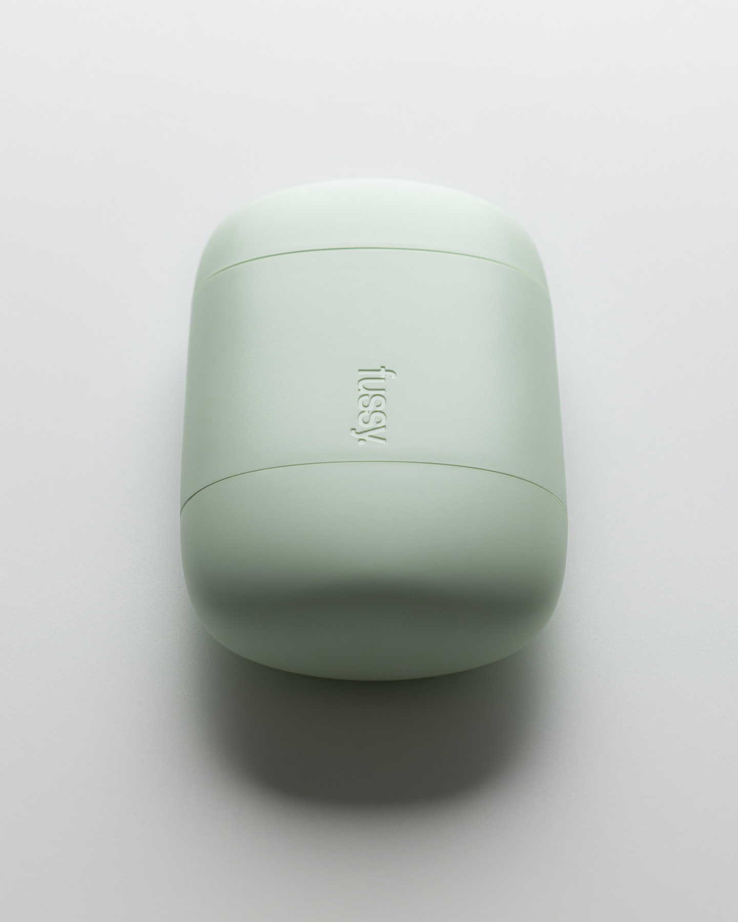 Top view of a closed mint green Fussy refillable deodorant case on a white surface.