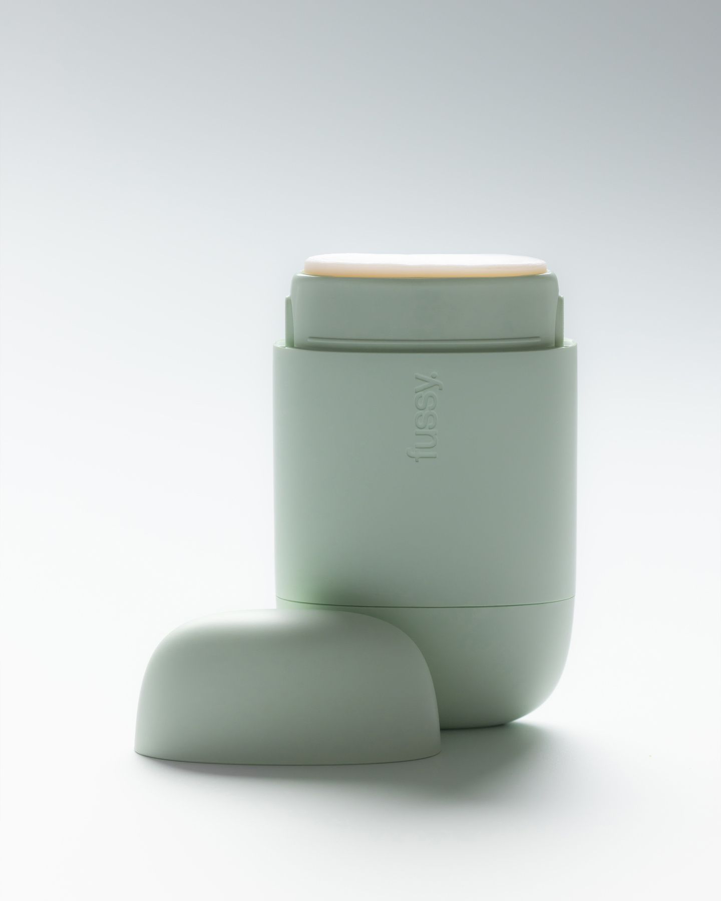 Open mint green Fussy deodorant case with the cap removed, resting on a white surface.