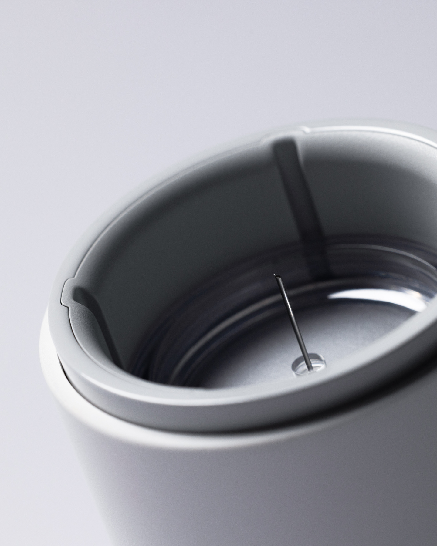 Close-up view of the inner base of a white continuous glucose monitor applicator showing an exposed needle