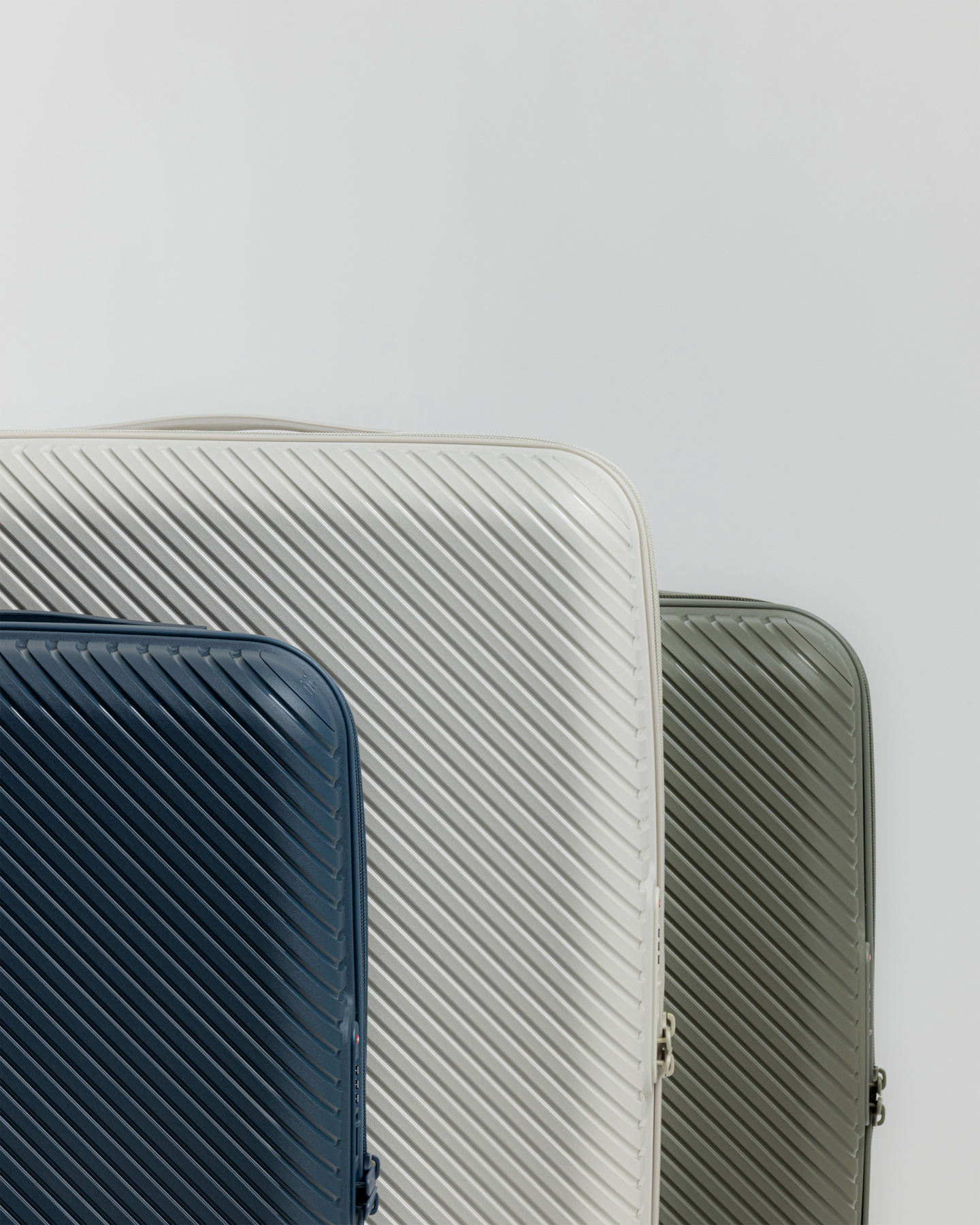 Blue, grey, and green hardshell suitcases standing side by side