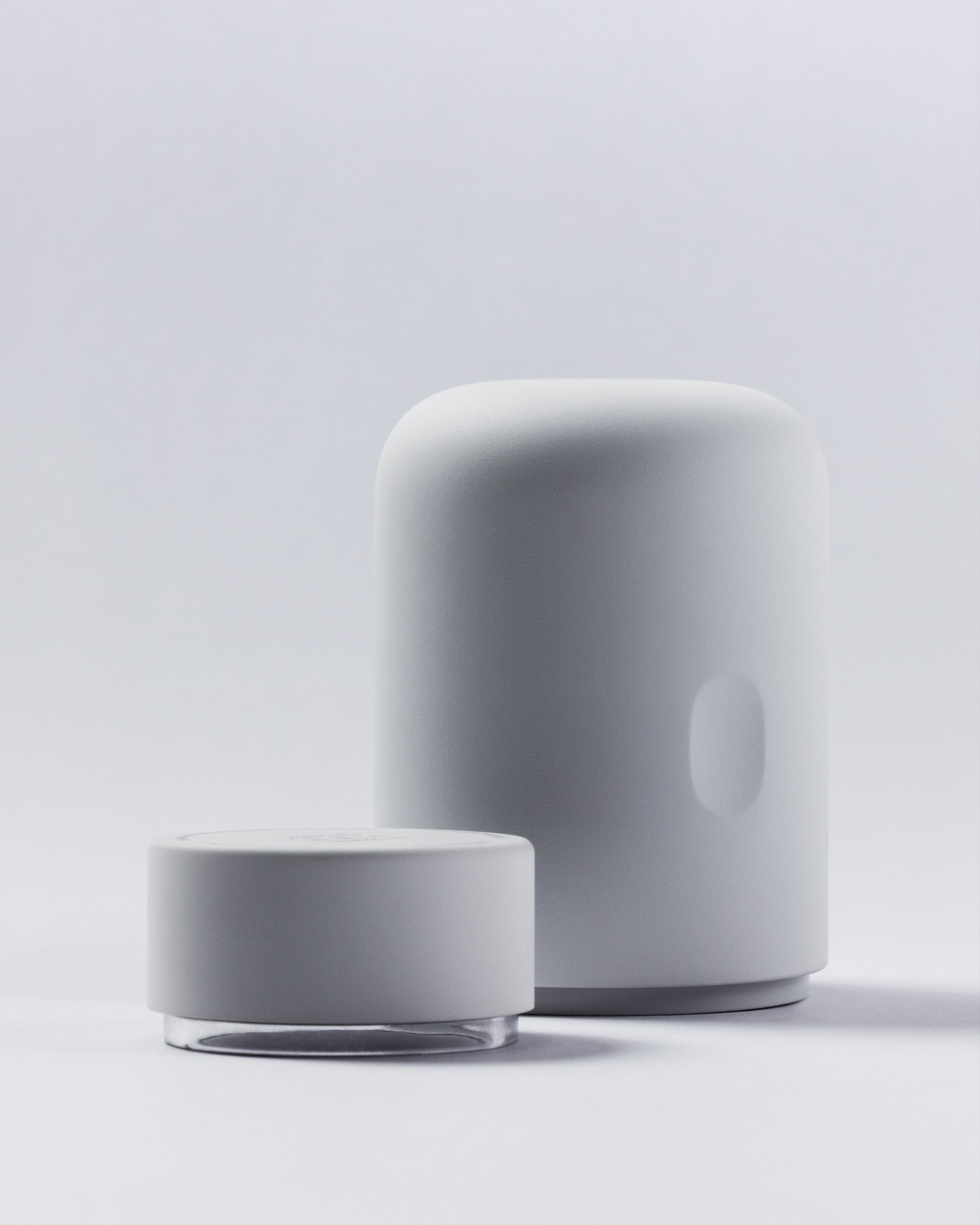 White continuous glucose monitor applicator standing next to a low-profile circular wearable sensor