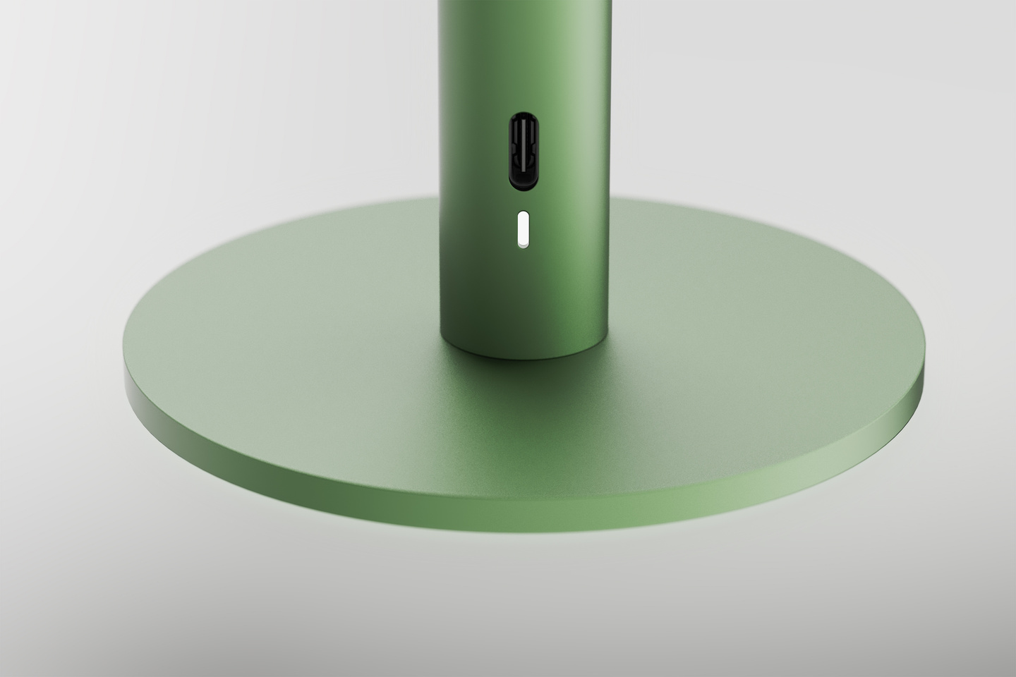 Close-up view of the circular base and charging port of a green Parasol Lamp.