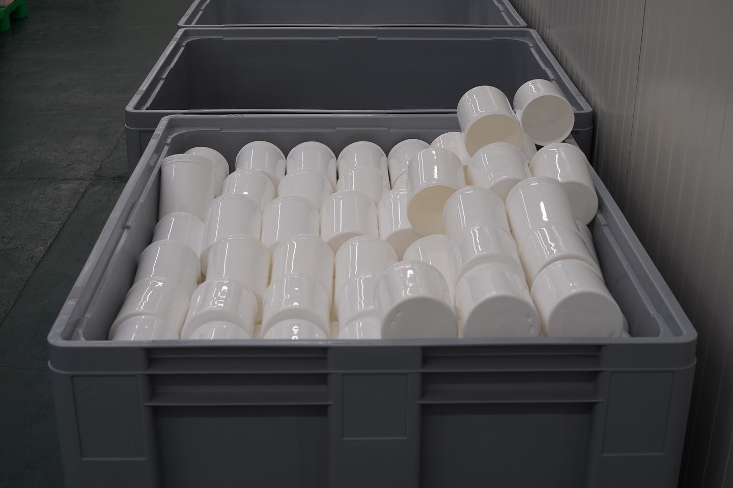 Industrial crate filled with rows of white reusable plastic container pots.