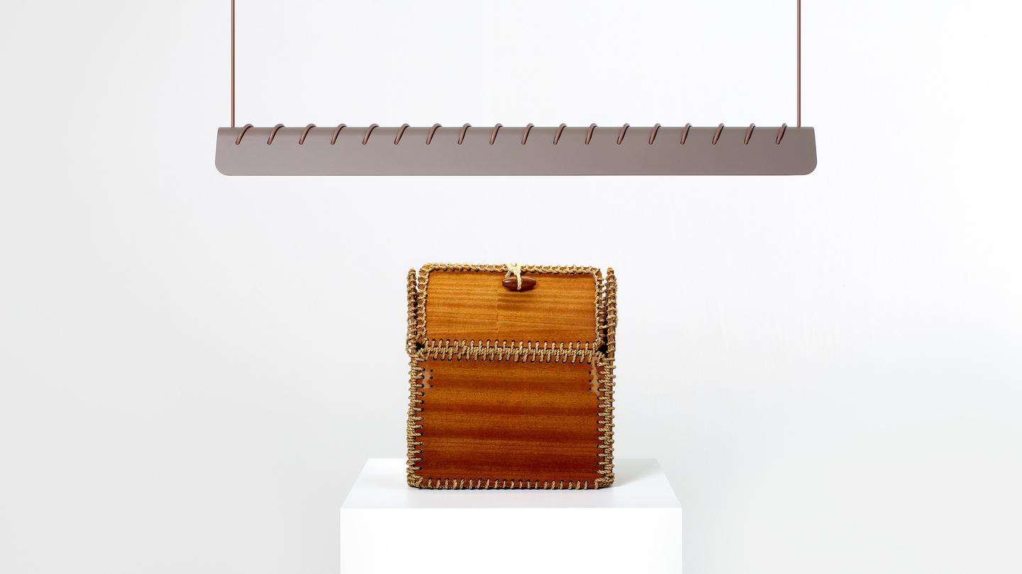 Linear light fixture suspended above wooden box on white plinth