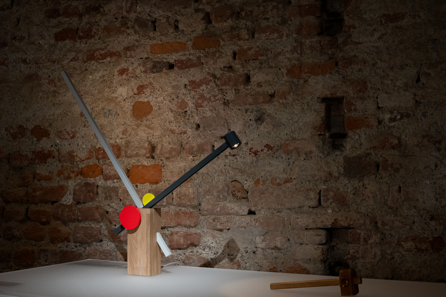 Small illuminated prototype object displayed against exposed brick wall