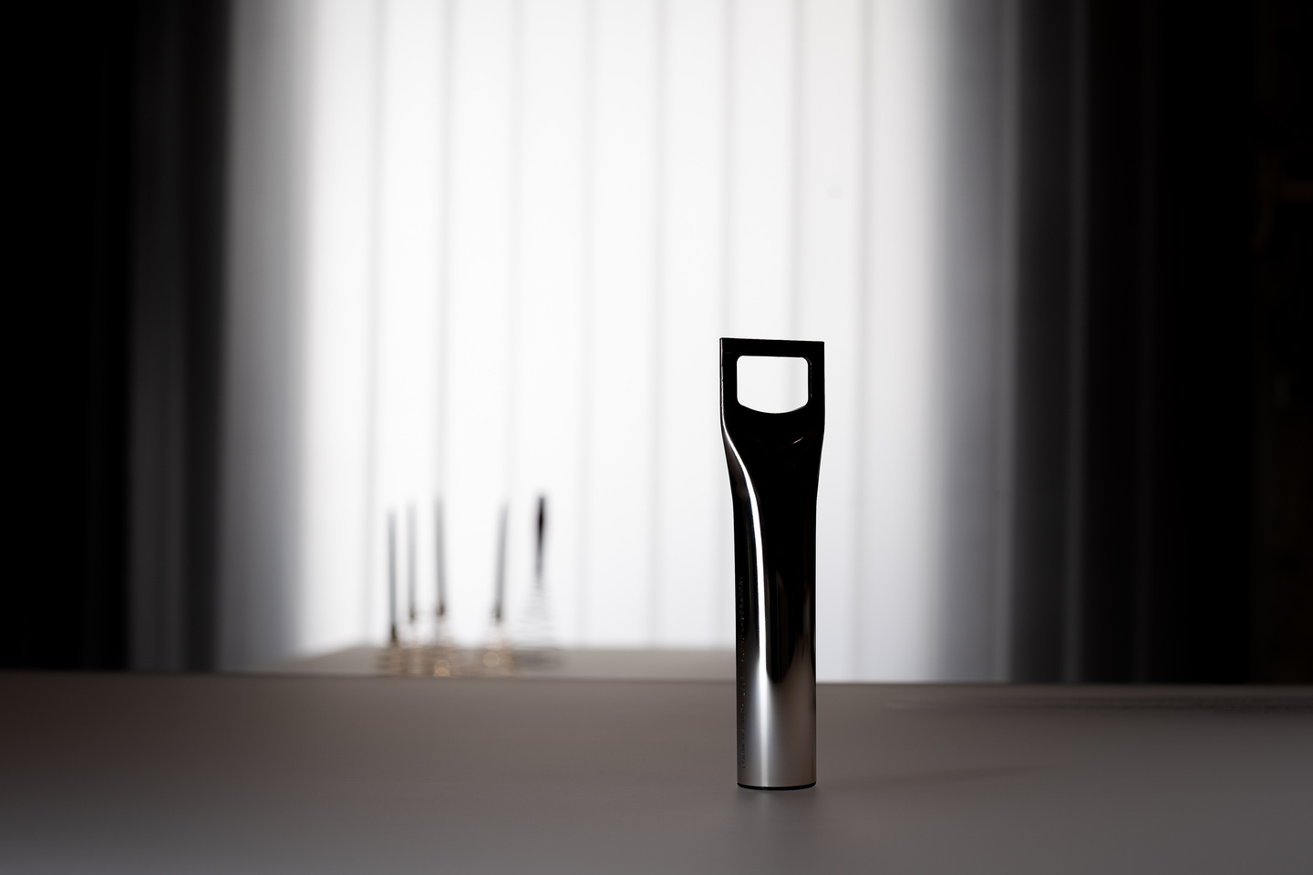 Bottle opener presented vertically in dark exhibition room