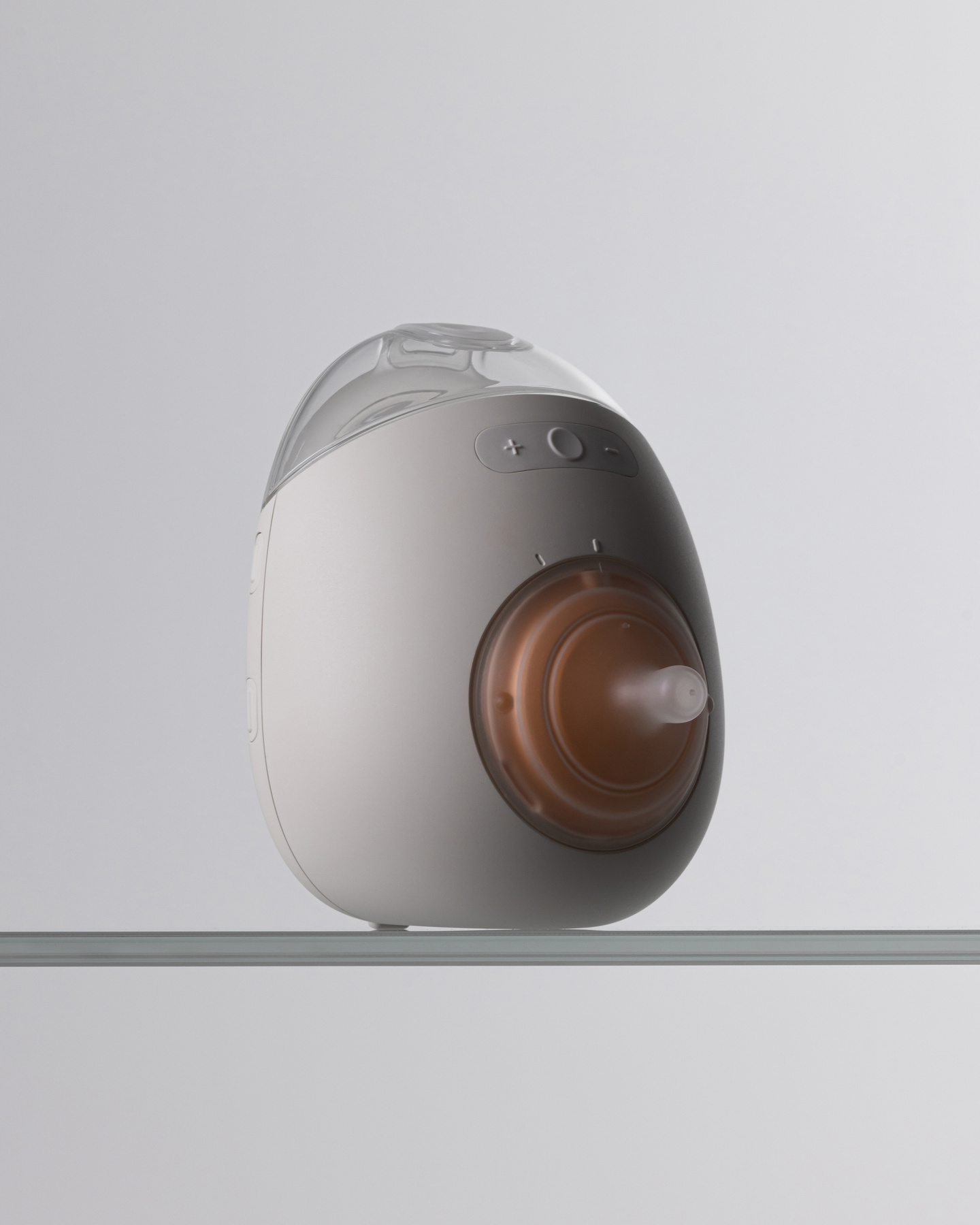 Studio shot of the white Avira wearable breast pump unit resting on a light surface.