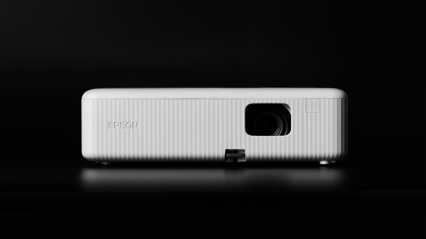 Distant front view of a white home projector on dark background