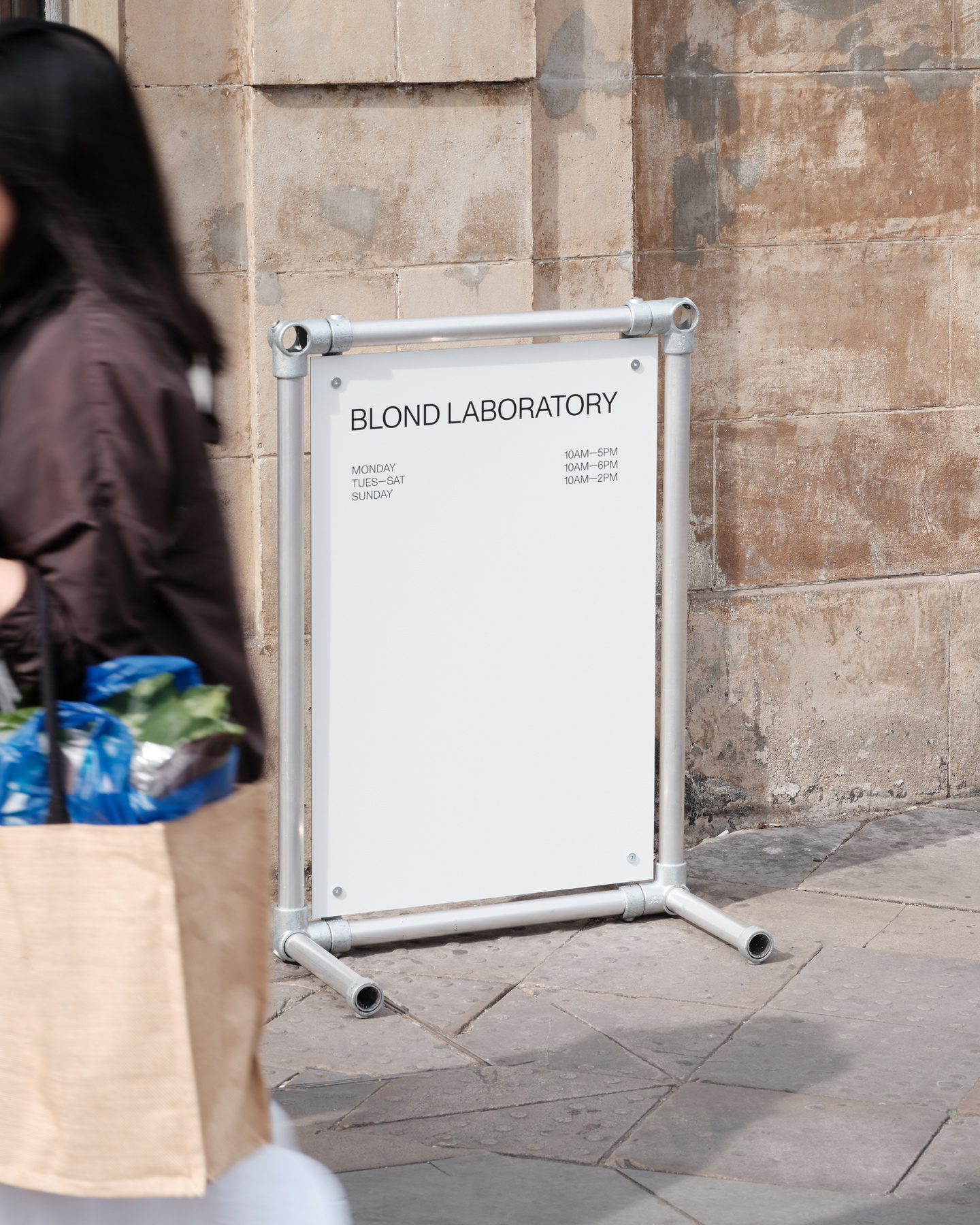 Person walking past white pavement sign outside exhibition venue