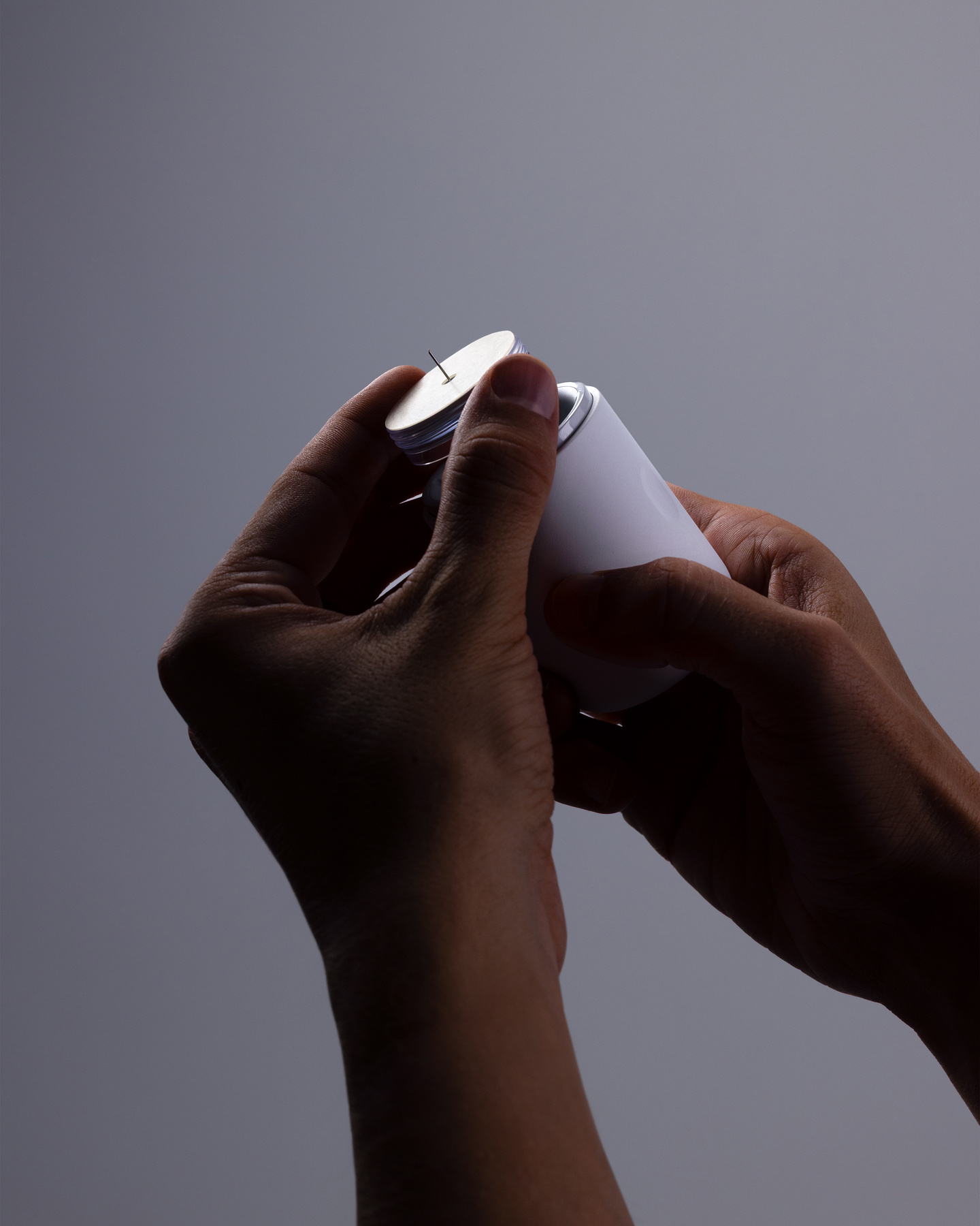 Hands loading a circular needle disk component into the top of a white continuous glucose monitor applicator