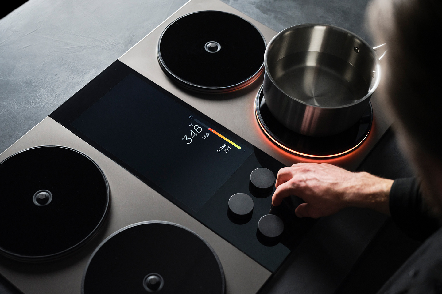 Overhead view of a hand cooking with a pot on an induction stovetop