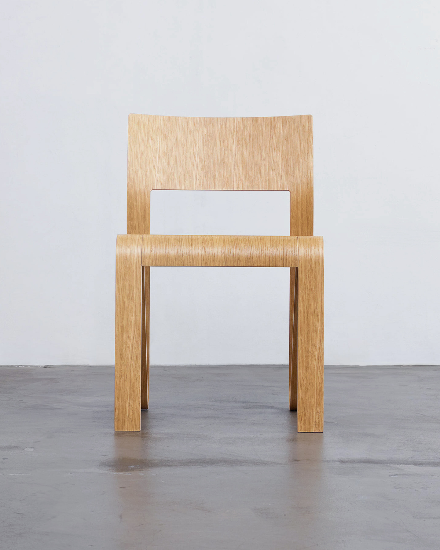 Wooden chair made from plywood photographed on a concrete floor.