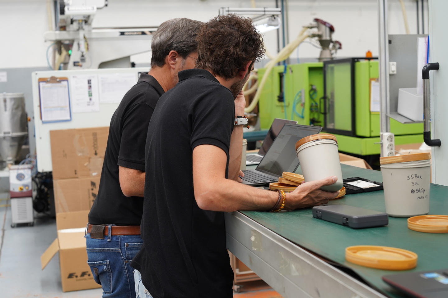 Two design engineers inspecting container production equipment in a factory.