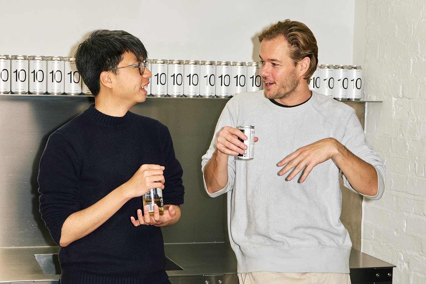 Two persons discussing with a drink in hand.