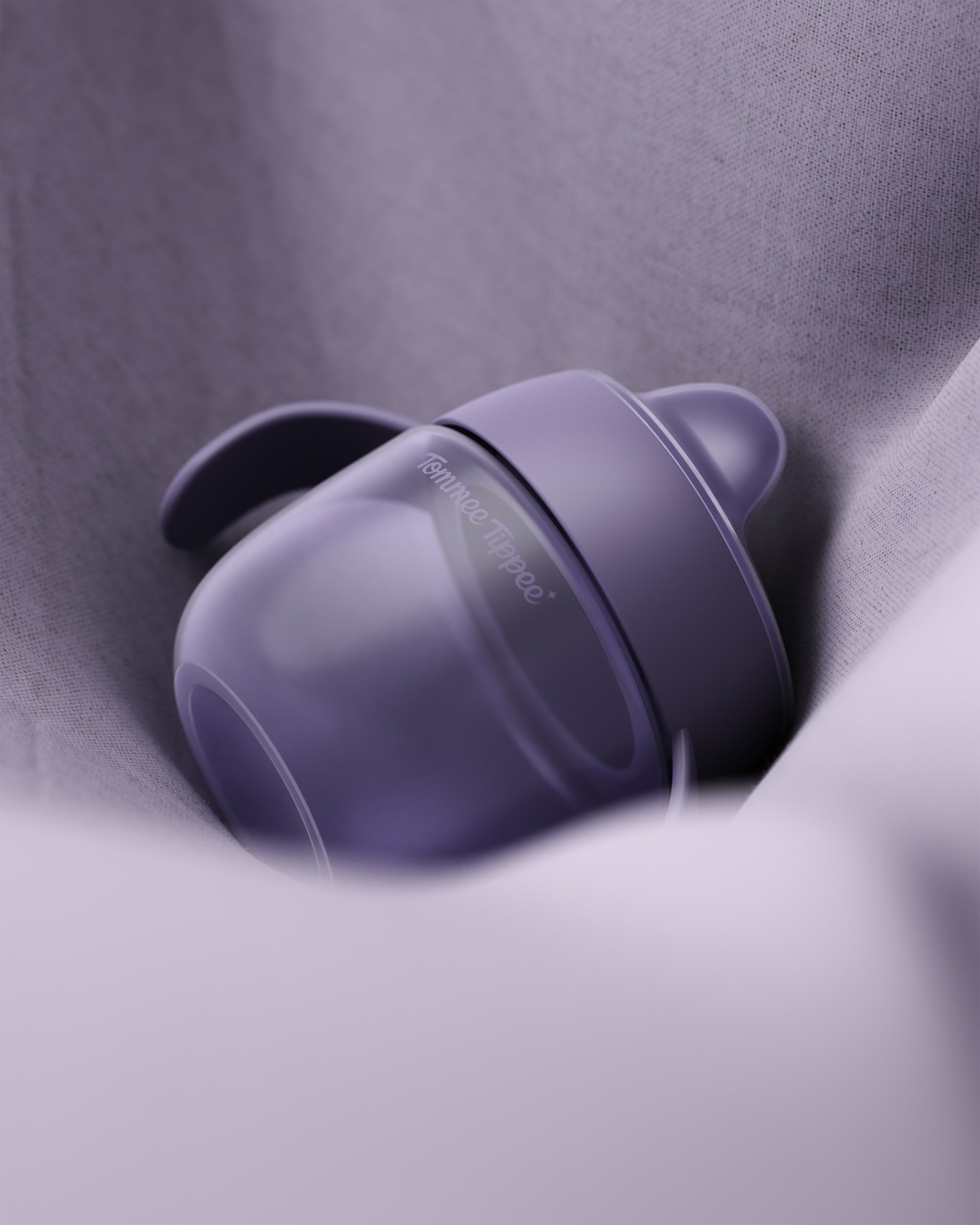 Close-up of a purple plastic cup resting on draped purple fabric
