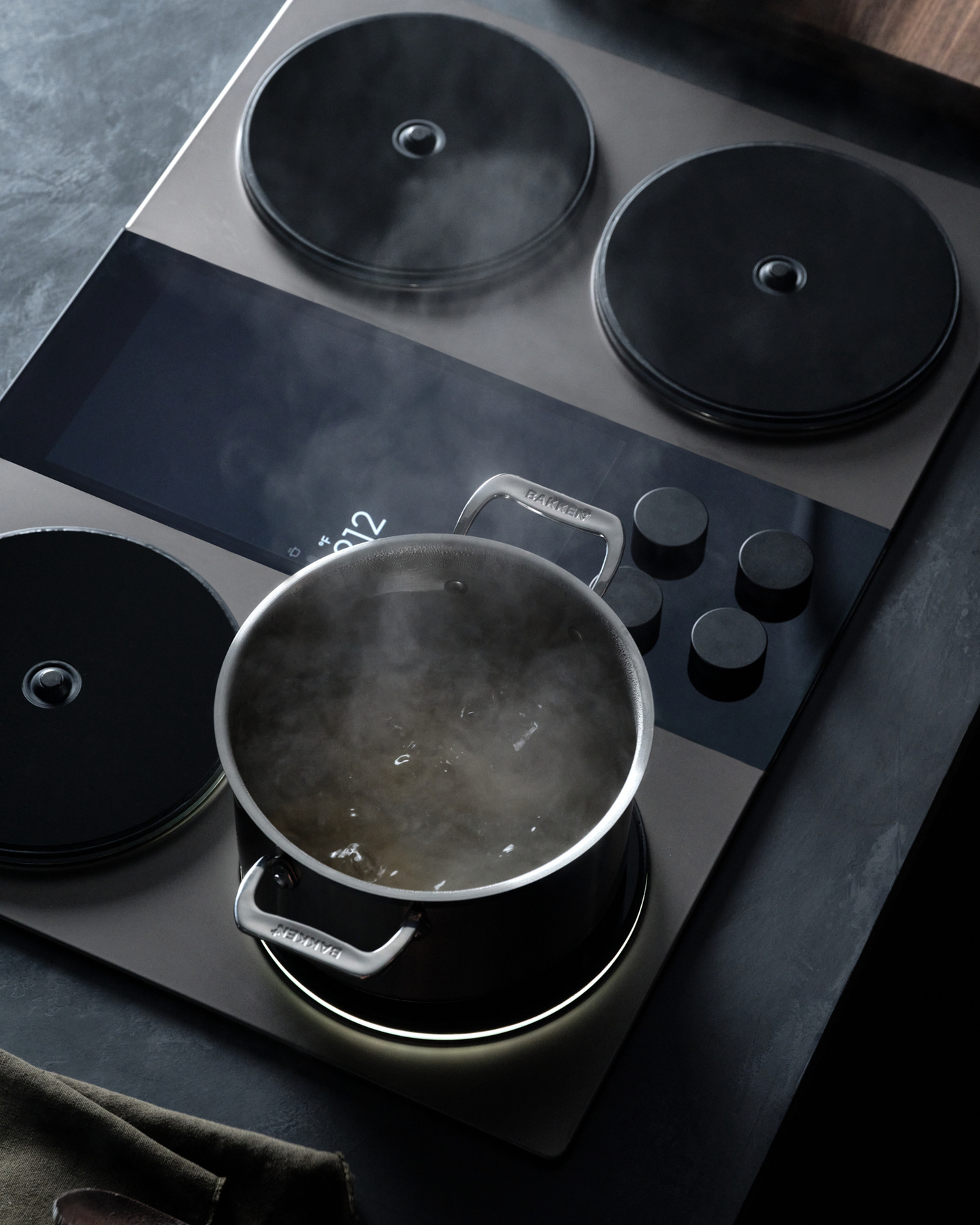 Pot boiling water on an induction stovetop burner next to a phone