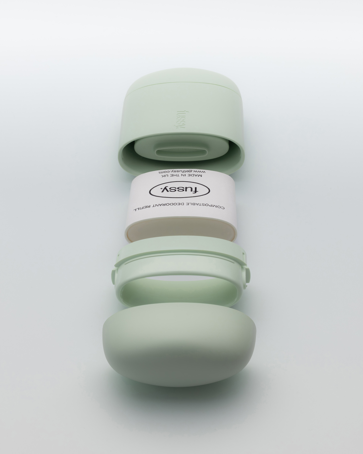 Small mint green Fussy deodorant case standing beside a white refill pod.