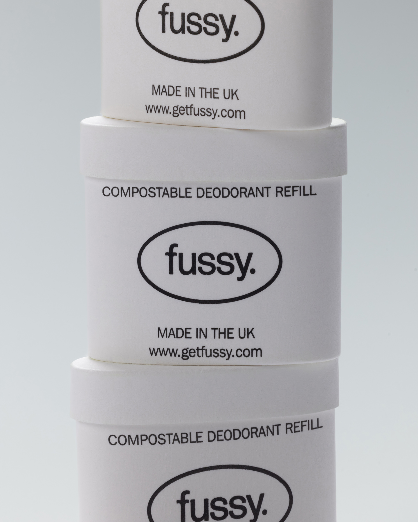 Three white Fussy deodorant refill pods stacked vertically showing the logo.