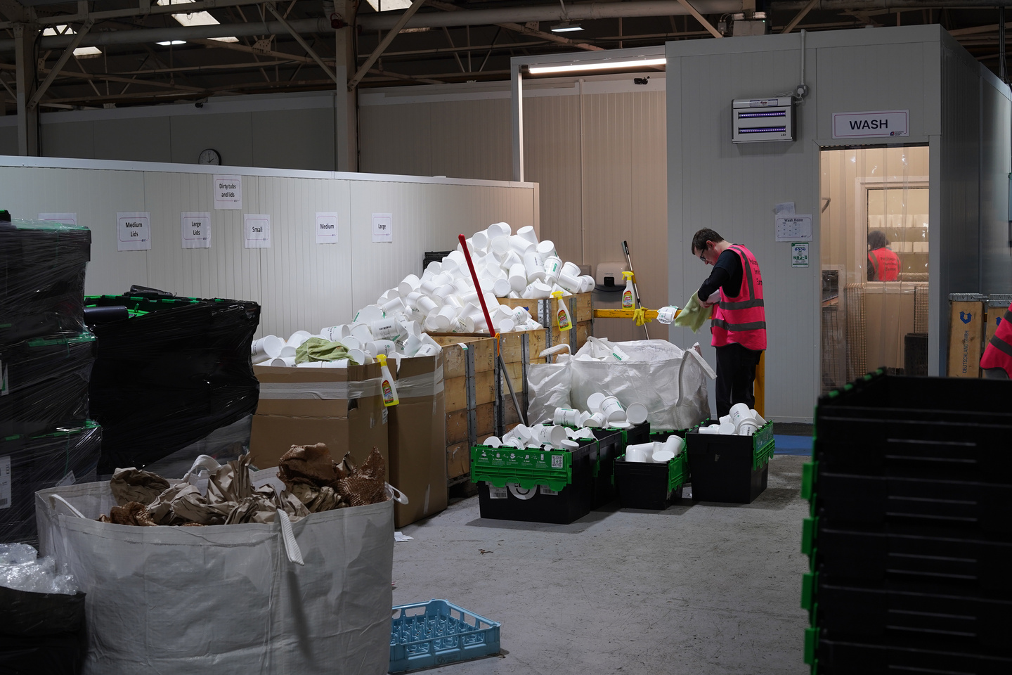 Factory floor space with pallets and equipment for reusable container processing.