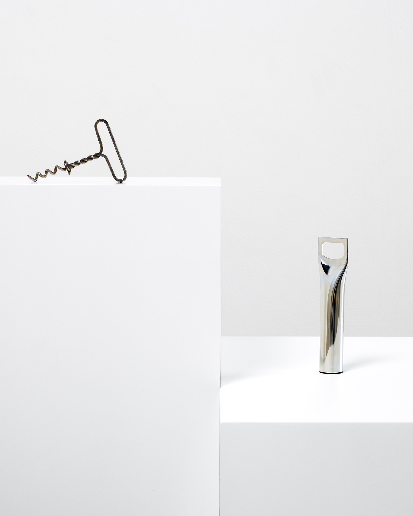 Minimalist metallic object displayed on tall white plinth